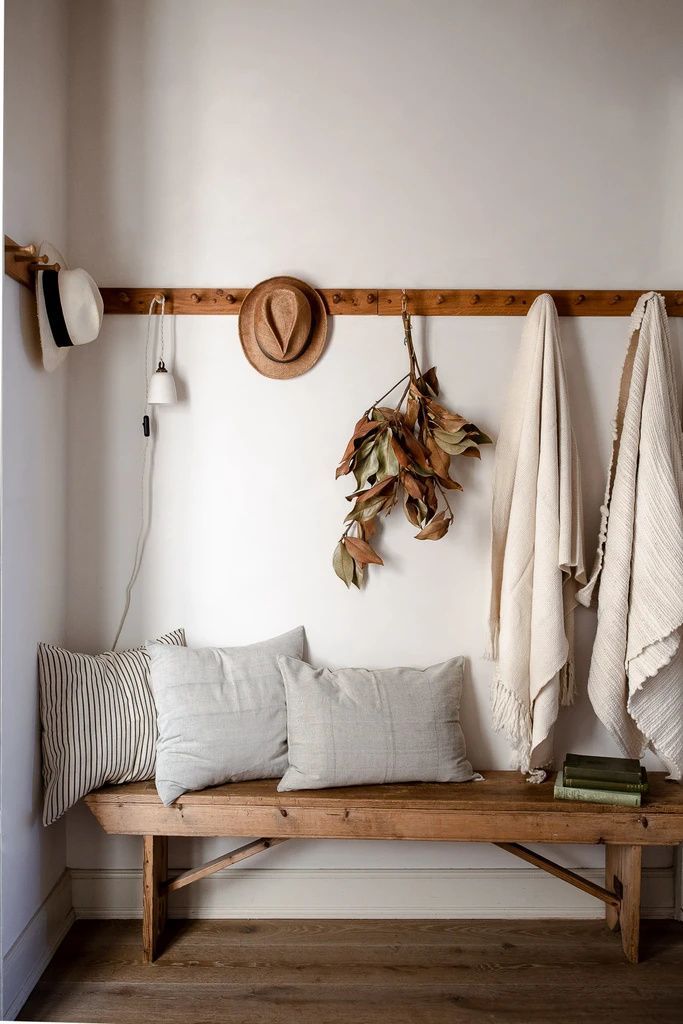 a wooden bench sitting next to a wall filled with pillows and blankets on top of it