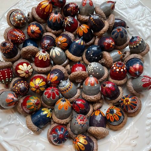 a white plate topped with lots of different types of painted glass balls on top of a table