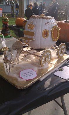 a table topped with a cake shaped like a horse drawn carriage and pumpkins on top of it