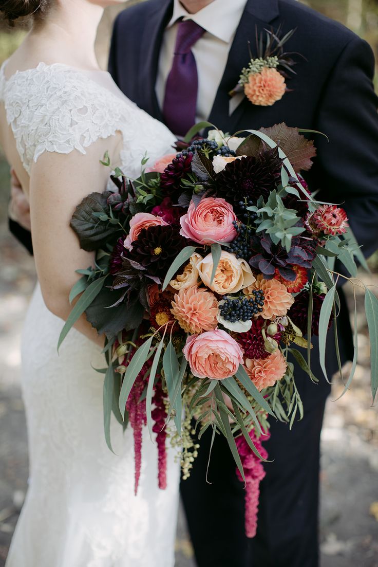 the bride and groom are posing for a wedding photo with their bouquet in front of them