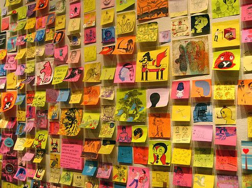 a wall covered in post it notes with pictures and words written on the back walls