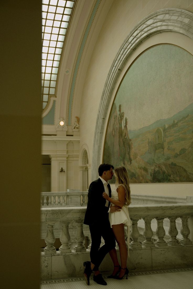 a man and woman standing next to each other in front of a painting on the wall