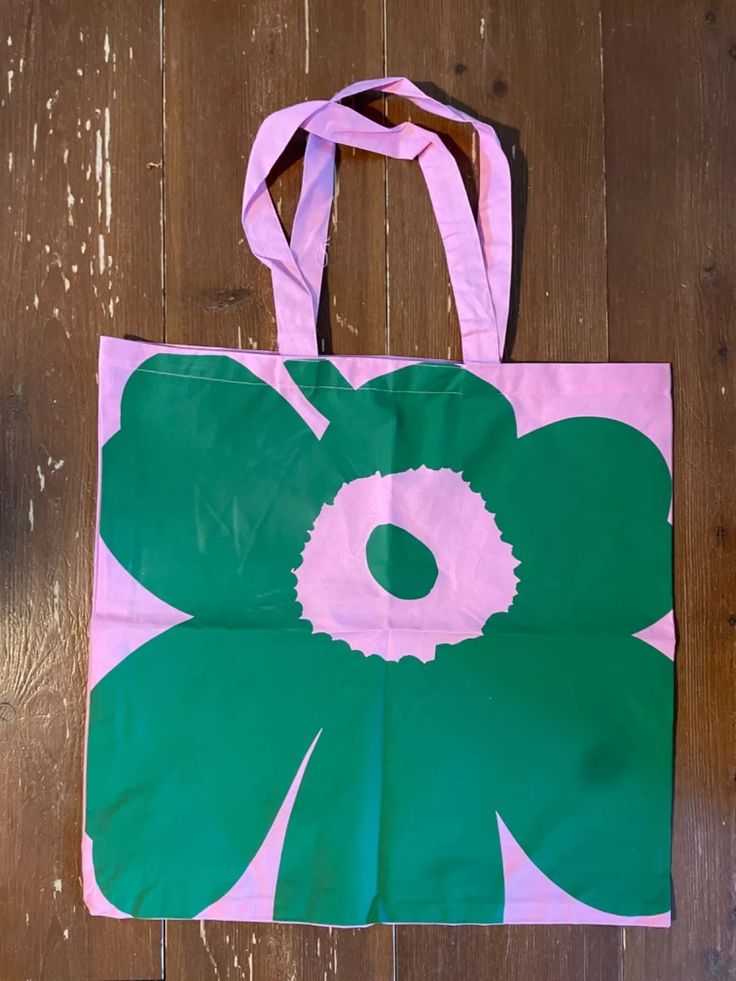 a pink and green flower bag sitting on top of a wooden floor next to a pair of scissors