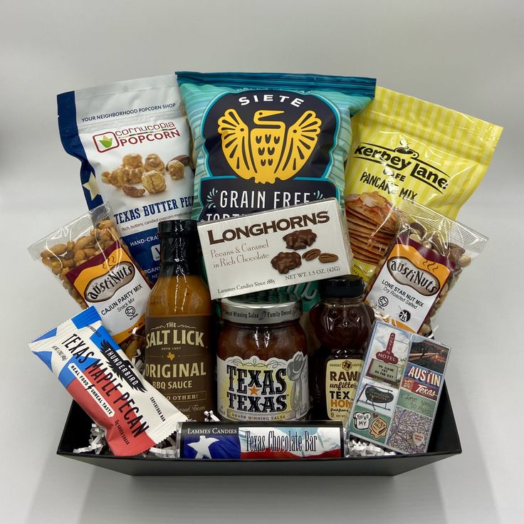 an assortment of snacks and condiments in a black tray on a white background