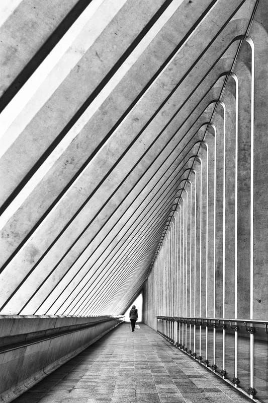 black and white photograph of a person walking in a tunnel