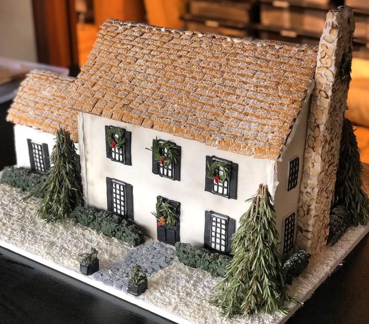 a white house with trees and bushes on the front porch is decorated in christmas decorations