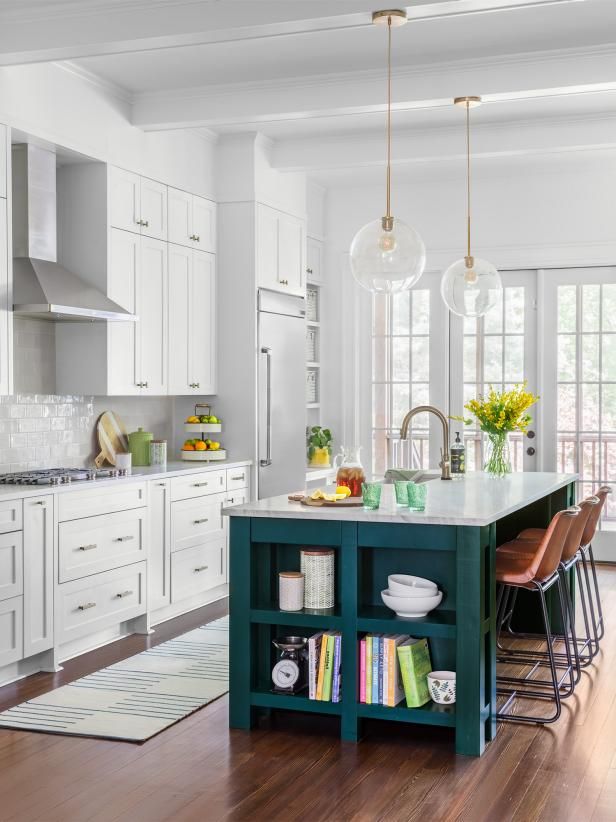 an open kitchen with white cabinets and green island in the center is surrounded by bookshelves