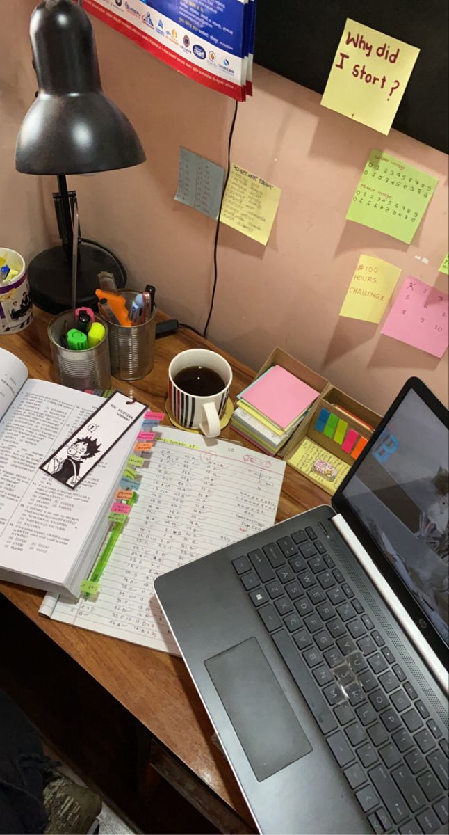 a laptop computer sitting on top of a wooden desk next to a cup of coffee