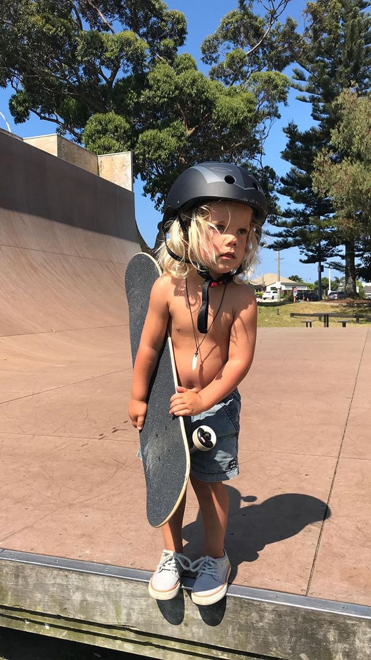 a small child wearing a helmet and holding a skateboard