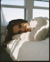 a woman laying on top of a bed next to a window