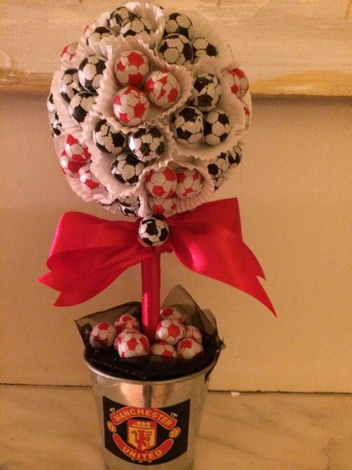 a bouquet of soccer balls in a bucket with a red bow on the top and a manchester united pin