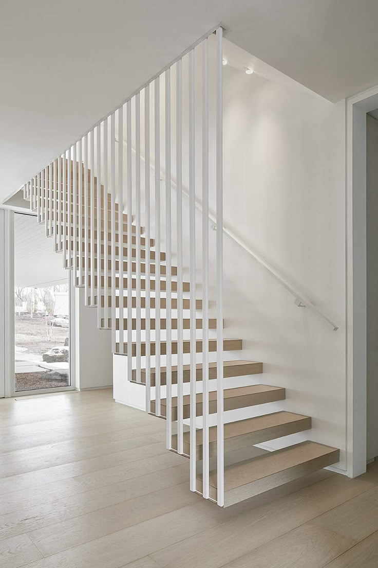 a white staircase with wooden handrails in an empty room