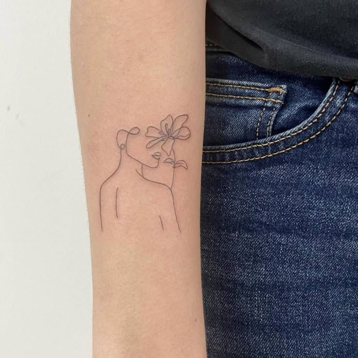 a woman's arm with a small tattoo of a dog holding a flower on it