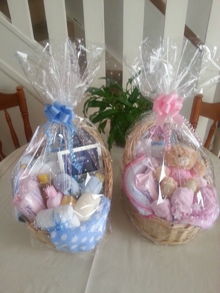 two baskets filled with baby items sitting on top of a white tablecloth covered table