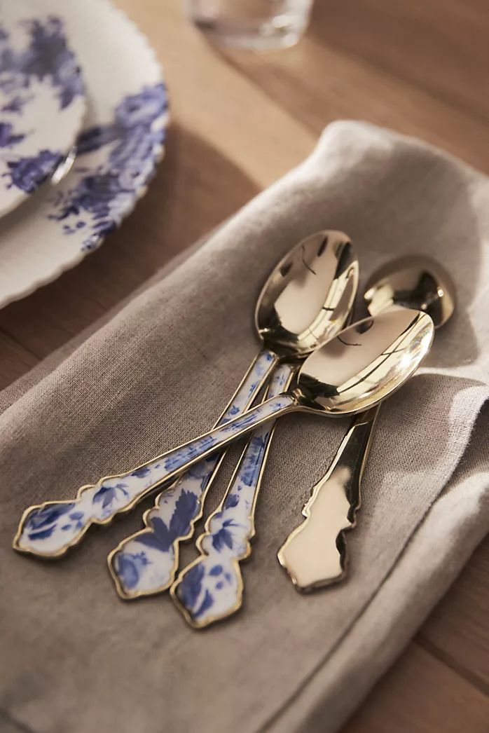 spoons and forks are sitting on a napkin next to a plate with blue flowers