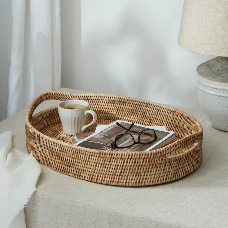 a wicker tray with coffee cup, eyeglasses and magazine sitting on it