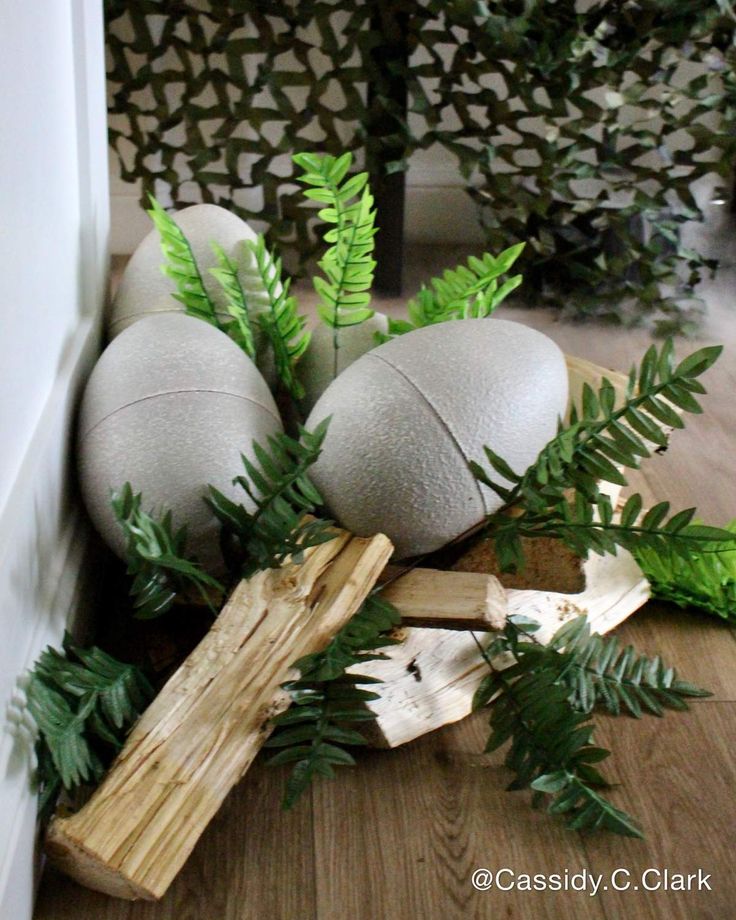 some balls and wooden sticks are on the floor next to green plants in front of a wall