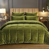 a bed with green comforter and pillows in a room next to a night stand