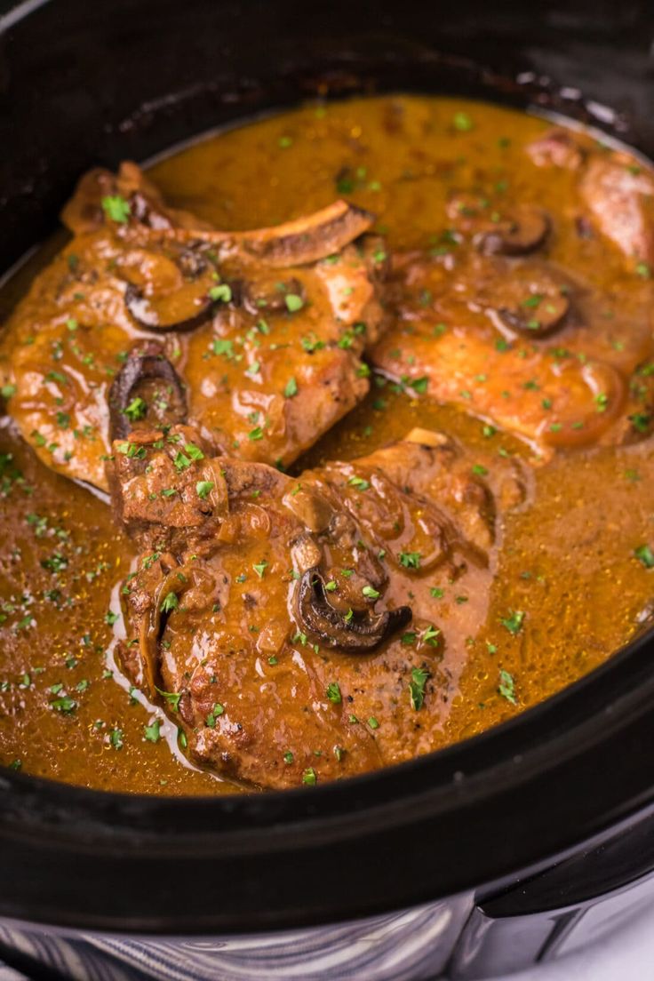 a crock pot filled with meat and mushrooms