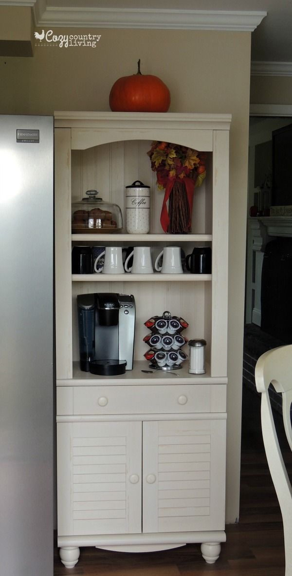 a kitchen with a refrigerator, coffee maker and other items on the shelves in front of it