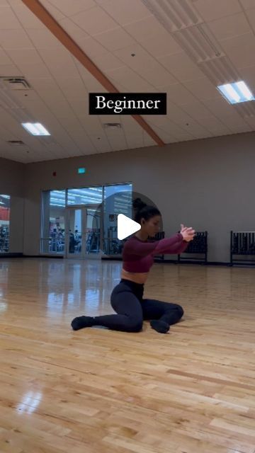 a woman is sitting on the floor in a dance studio and has her arms spread out