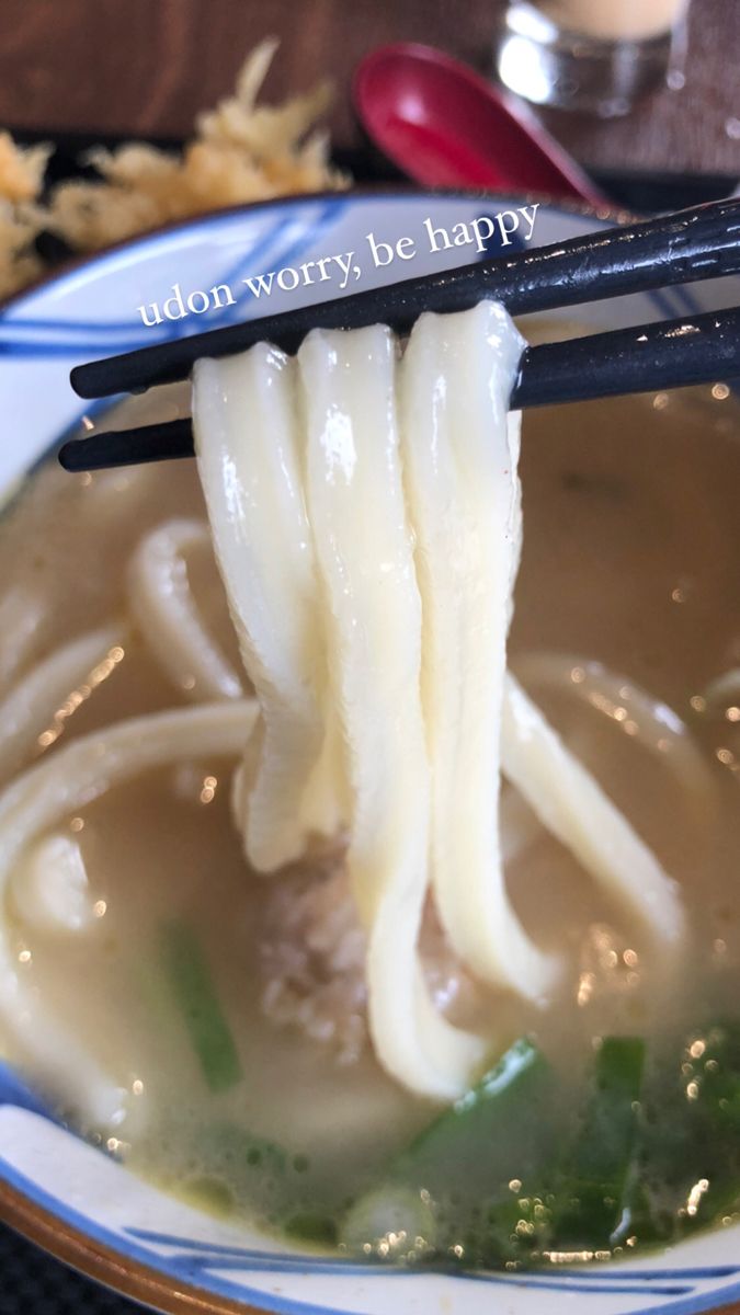 chopsticks holding noodles in a bowl of soup