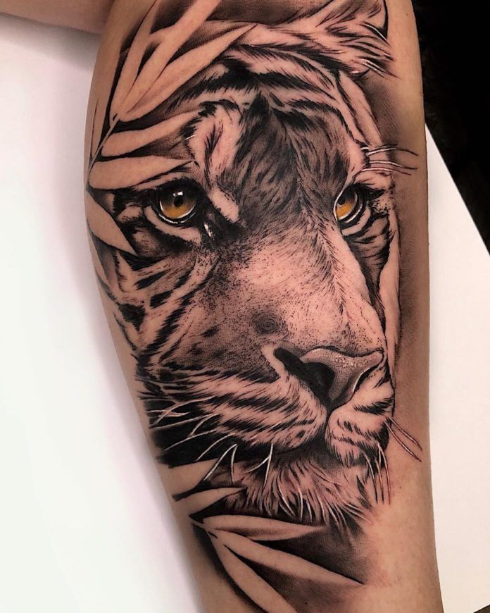 a close up of a tiger's face on a person's leg with tattoos