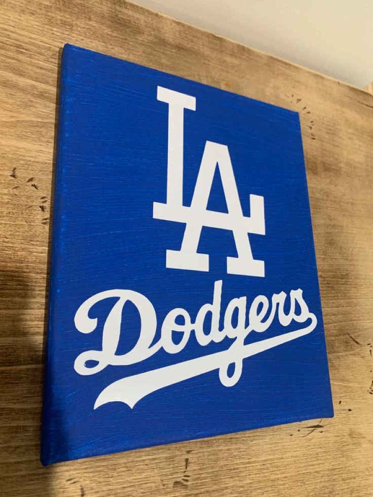 a los angeles dodgers sign mounted on the side of a wooden wall