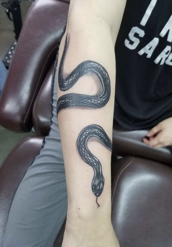 a man with a tattoo on his arm has a black and white snake on it