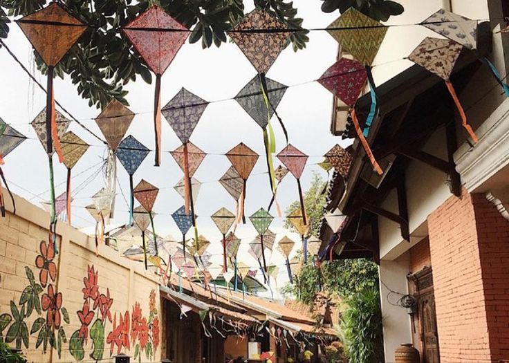 there are many kites hanging in the air on this building's side walk