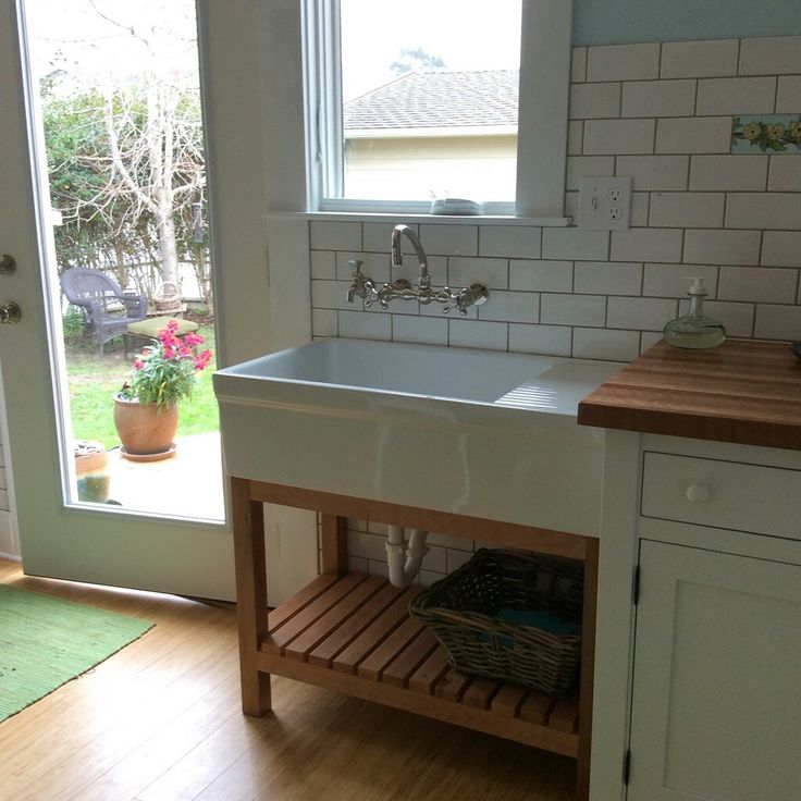 a kitchen with a sink and wooden counter top next to an open door that leads outside