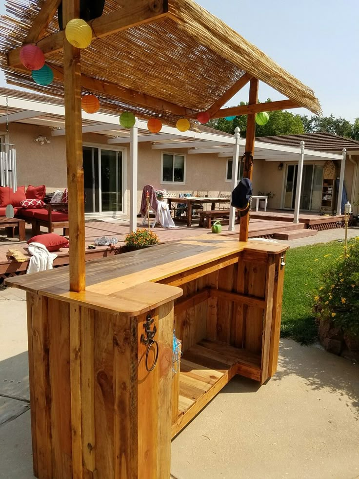 an outdoor bar made out of pallets and wooden planks is shown in front of a house