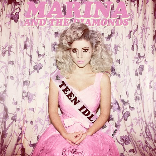 a woman wearing a pink dress sitting in front of a curtain with the words marina and the diamonds on it