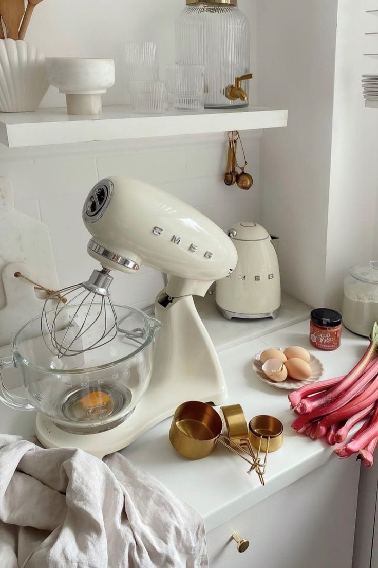 a white mixer sitting on top of a counter next to other kitchen items and utensils