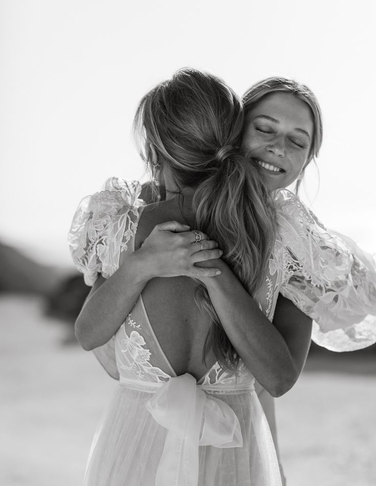 two women hugging each other on the beach