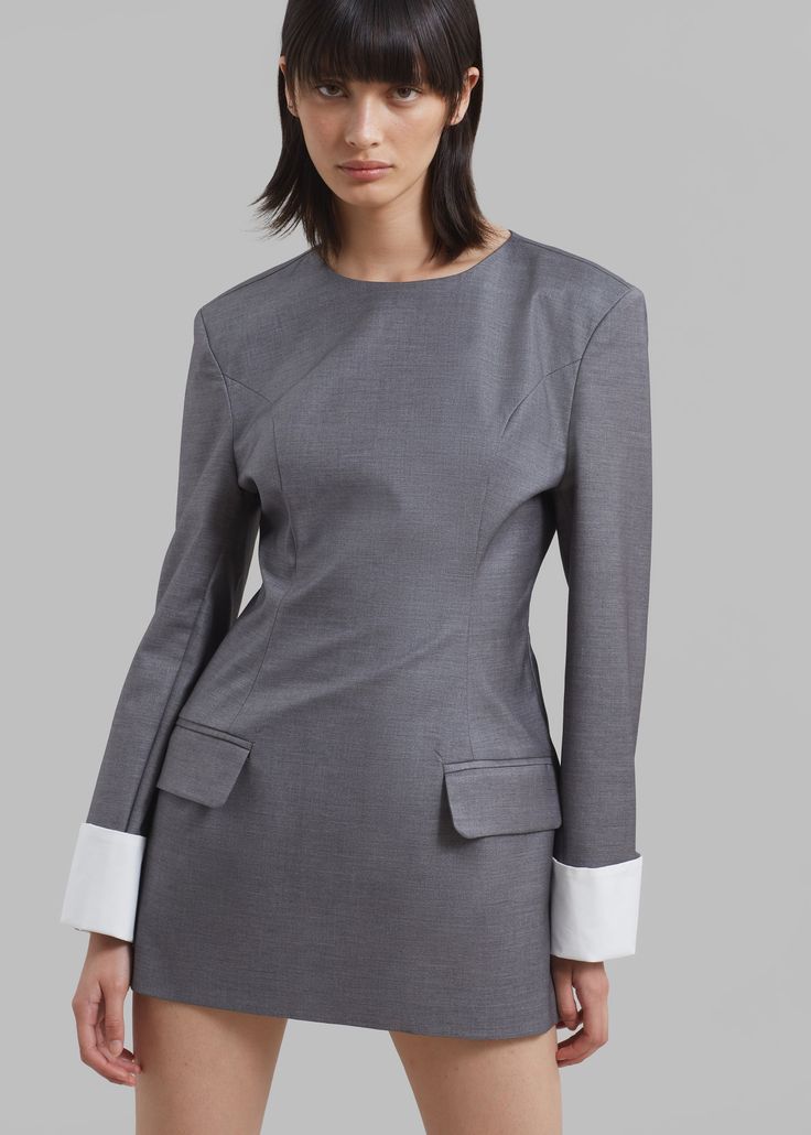 Color: Grey Midweight traditional suiting fabric Slim fit Mini length Round neck Padded shoulders Front flap pockets Contrast cuffs Concealed back zip closure Unlined 68% Polyester 20% Rayon 10% Wool 2% Elastane Dry Clean Imported Tailored Long Sleeve Dress With Structured Shoulders, Office Wear Suits With Button Cuffs, Workwear Dresses With Structured Shoulders And Long Sleeves, Long Sleeve Dresses With Structured Shoulders For Work, Fitted Workwear Dress With Set-in Sleeves, Formal Long Sleeve Dress With Cuffed Sleeves, Long Sleeve Business Dress With Pockets, Business Suits With Structured Shoulders And Long Sleeve, Structured Long Sleeve Suits For Semi-formal Occasions