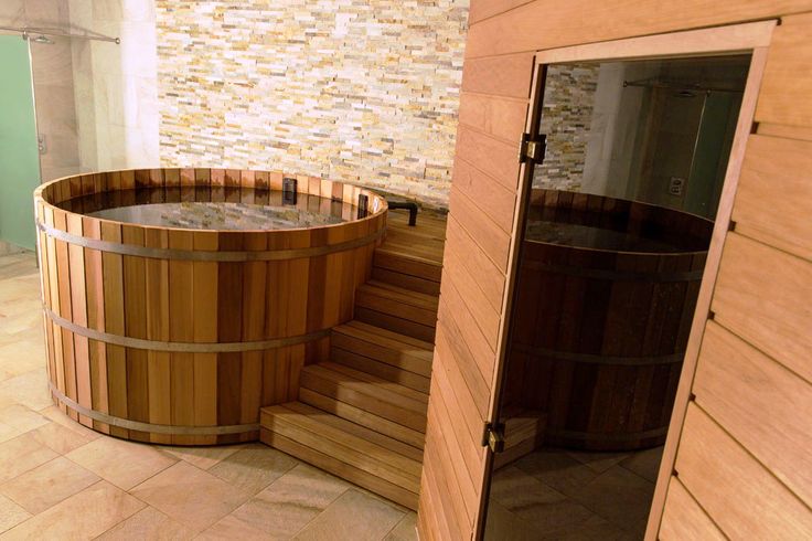 a wooden hot tub sitting inside of a bathroom next to a tiled wall and door