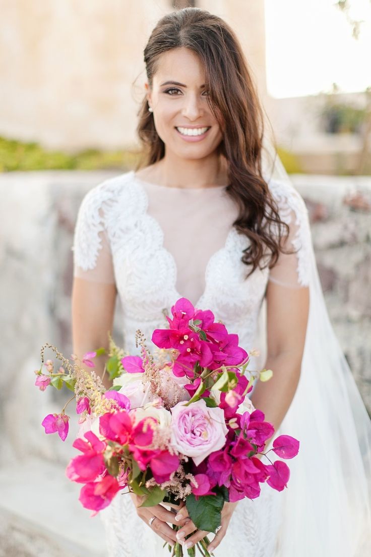 a woman in a wedding dress holding a bouquet of pink and white flowers on her left hand