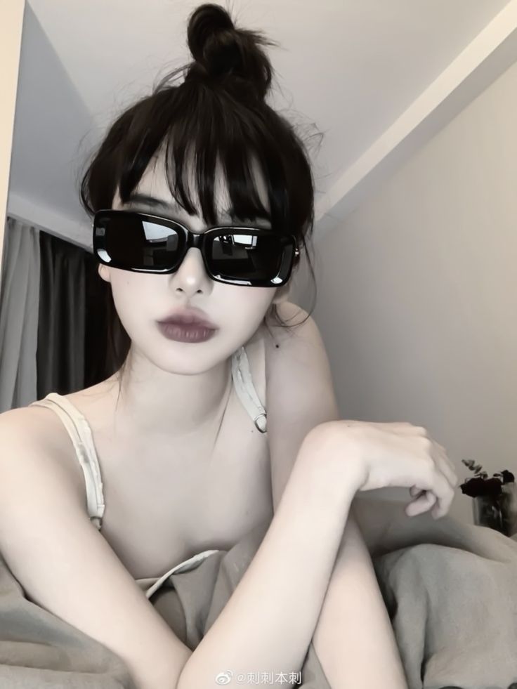 a woman wearing sunglasses laying on top of a bed