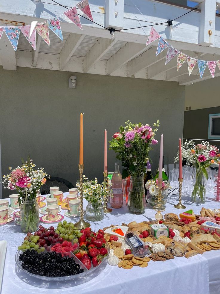 a table topped with lots of food next to candles and flowers on top of a white table cloth