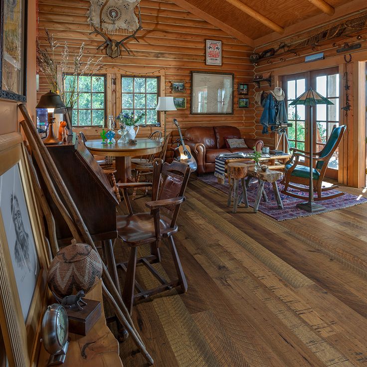 the inside of a log cabin with wood floors and tables, chairs, and pictures on the wall