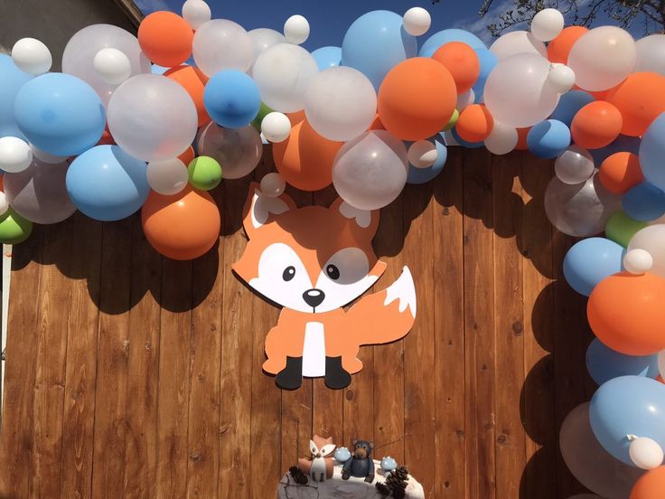 a wooden fence with balloons and decorations on it, including a fox cut out from the wall