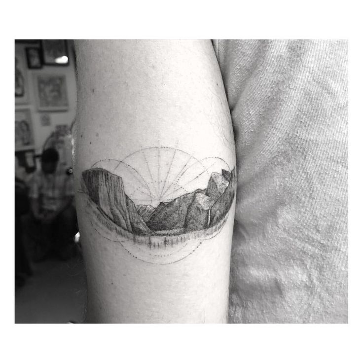 a man with a tattoo on his arm that has an image of mountains in it