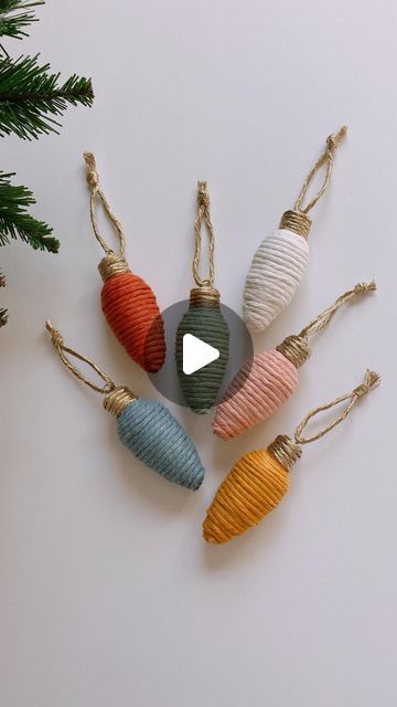 christmas ornaments hanging from twine cord on white wall with pine tree in the background