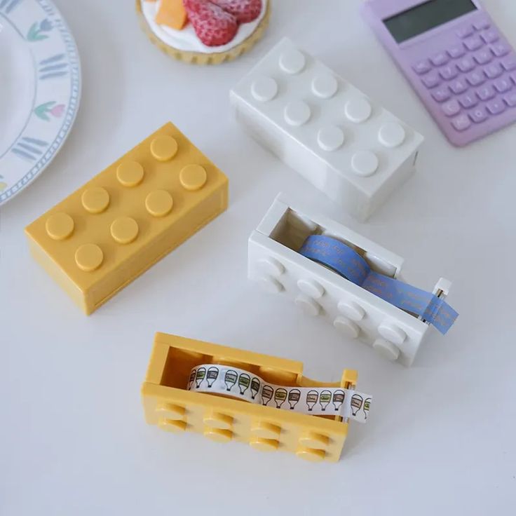 legos are arranged on a white table with plates, cups and utensils