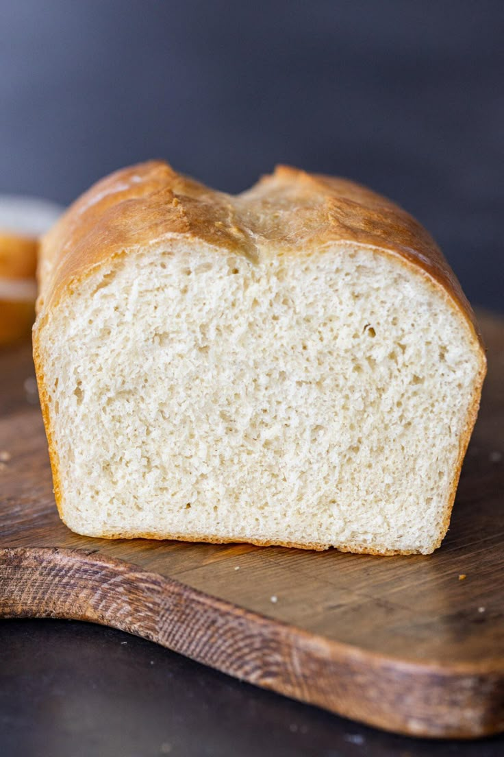 a loaf of white bread sitting on top of a wooden cutting board