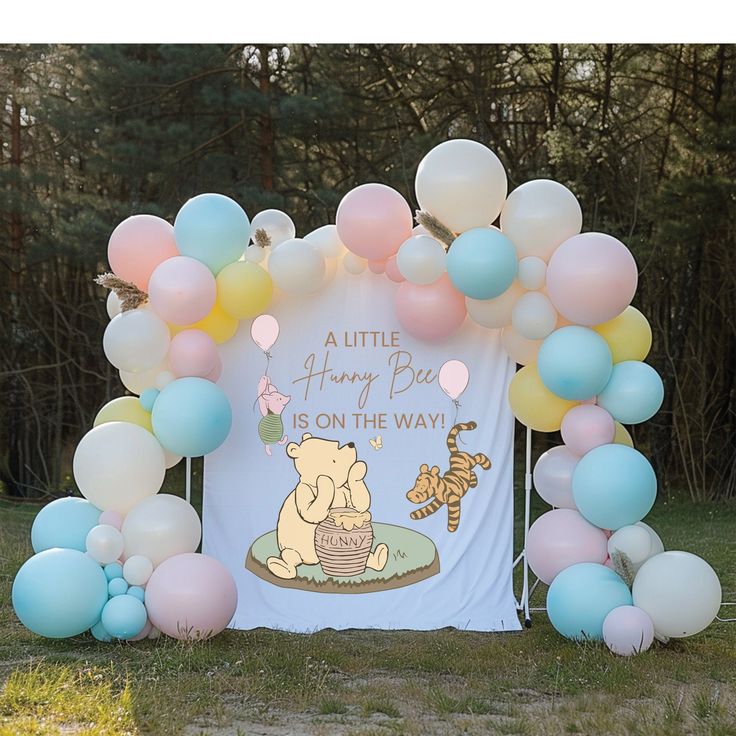 a winnie the pooh birthday party with balloons and streamers, including an arch