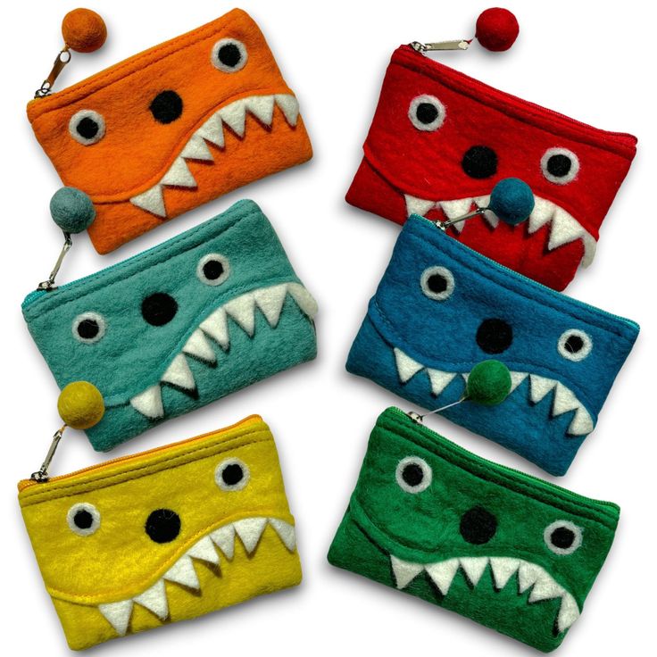 four different colored monster purses with teeth on them