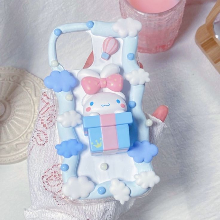 a hello kitty phone case sitting on top of a lace tablecloth next to a candle