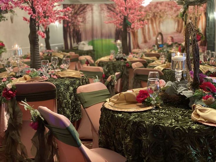 tables set up for an event with flowers and greenery on the tablecloths